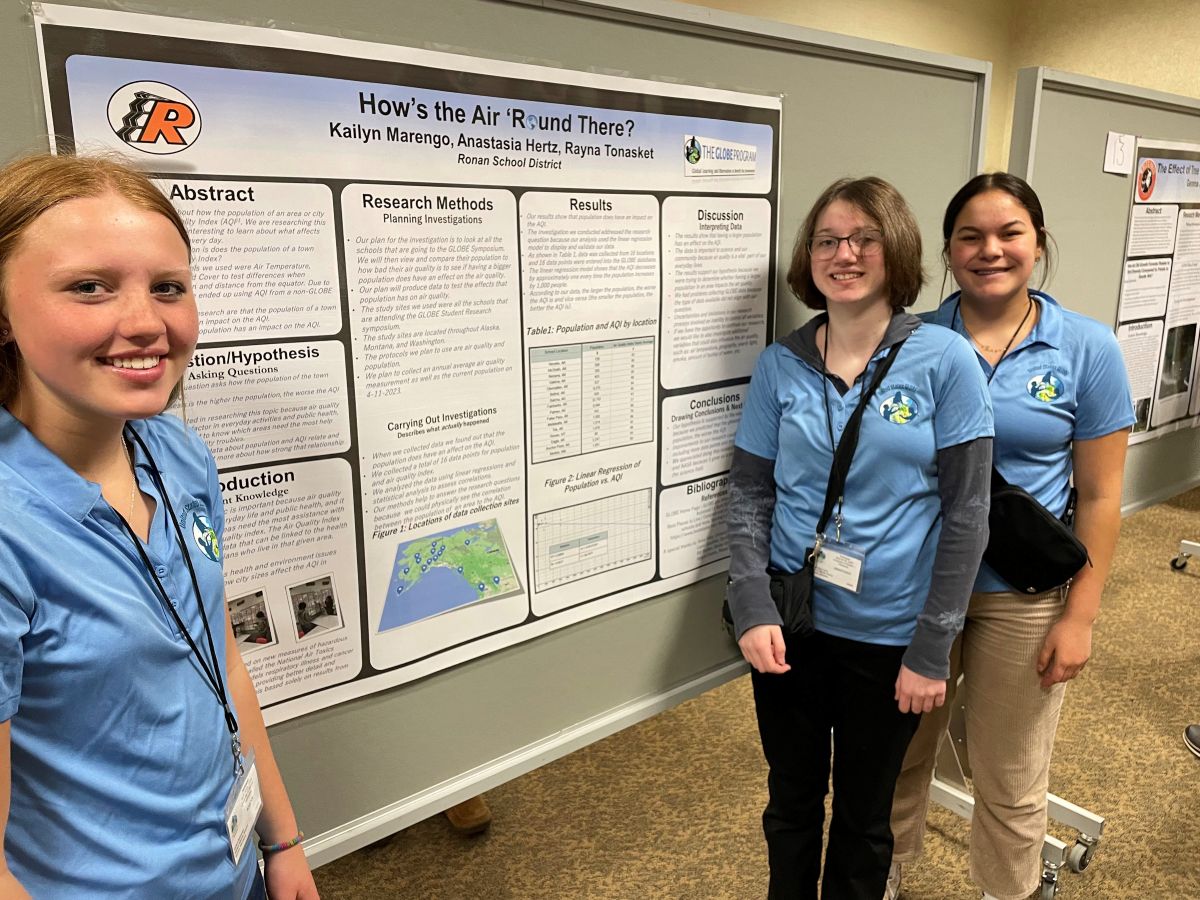 three students stand with their research poster