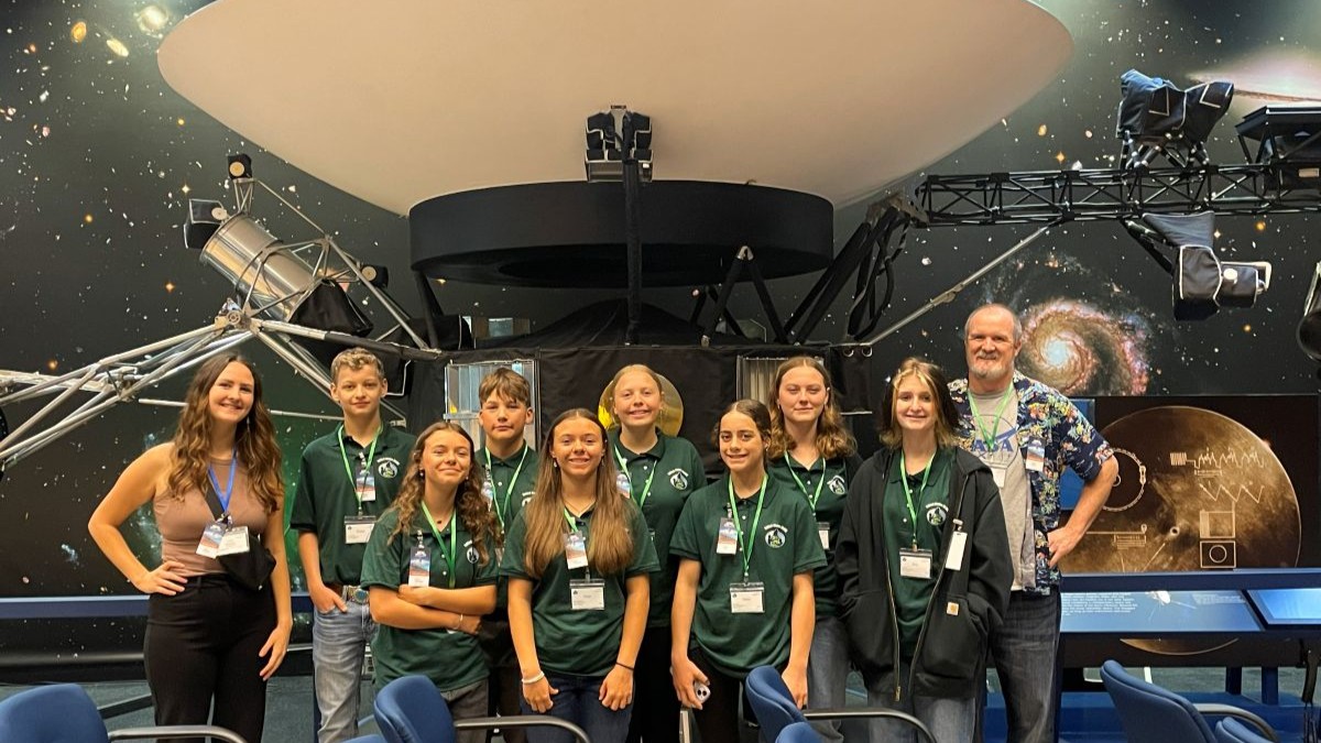 Ronan Middle School students stand in front of a display at the NASA Jet Propulsion Laboratory with their teacher and mentor 